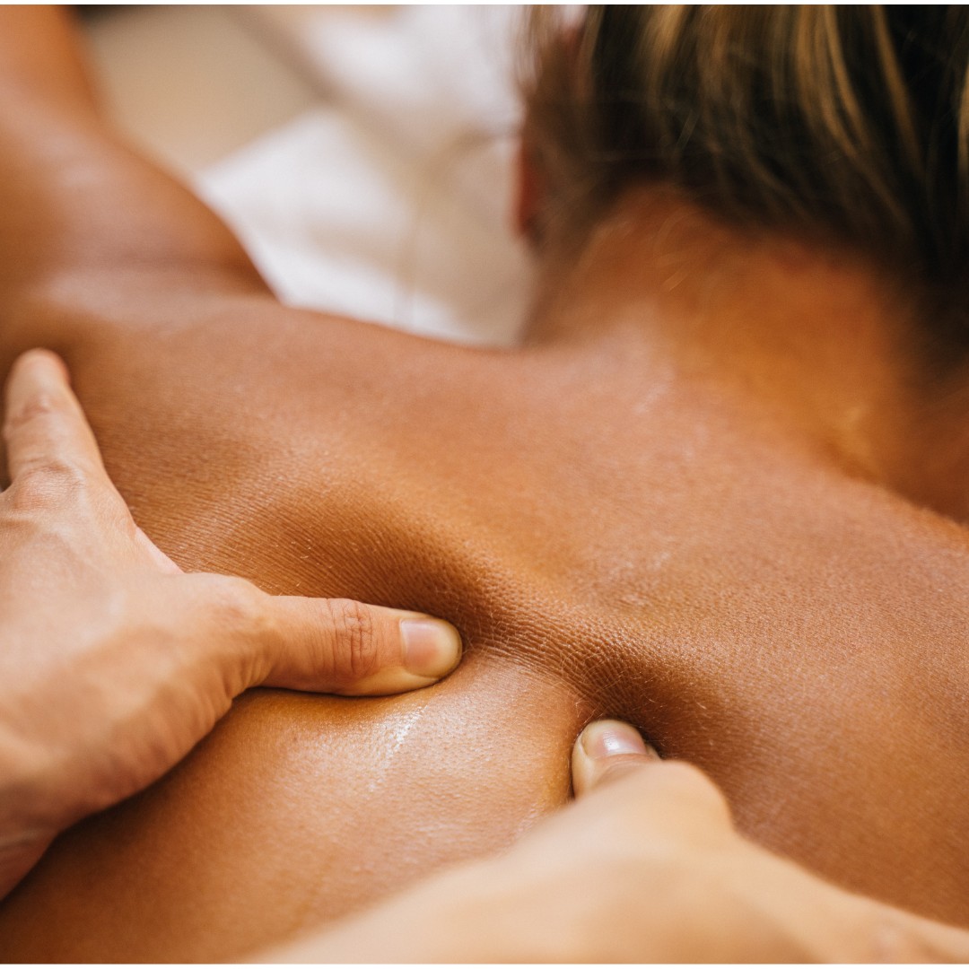 Therapist applying thumb pressure along a client's upper back